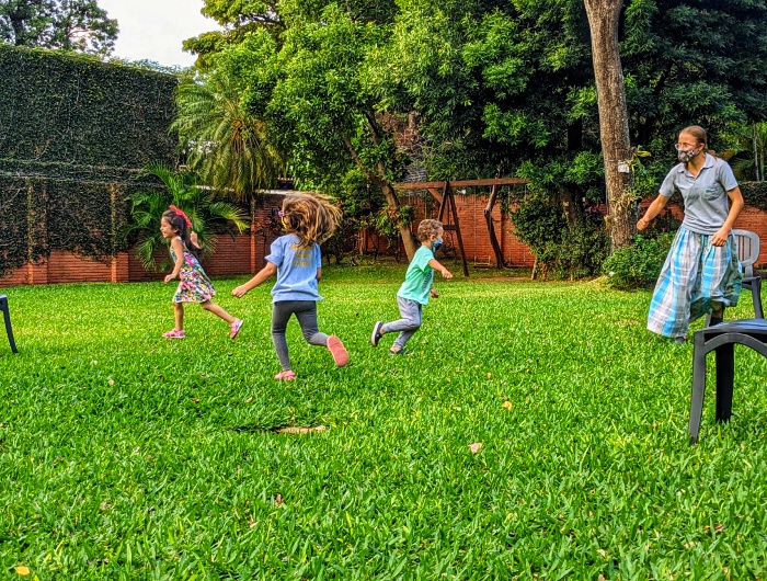 Children and teachers play a running game in a fun English class at Primavera English